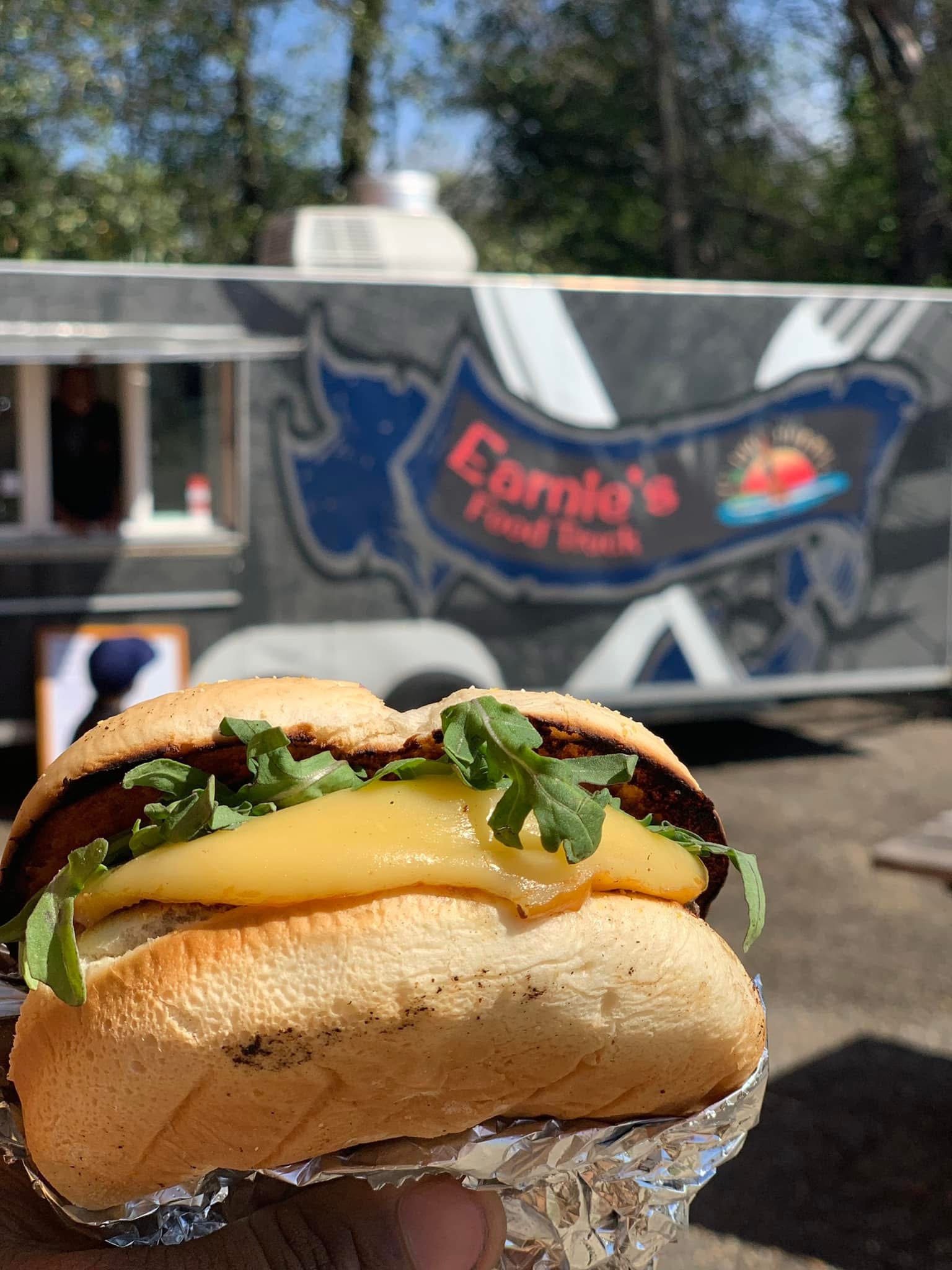 Cheeseburger held in front of Earnie’s Food Truck
